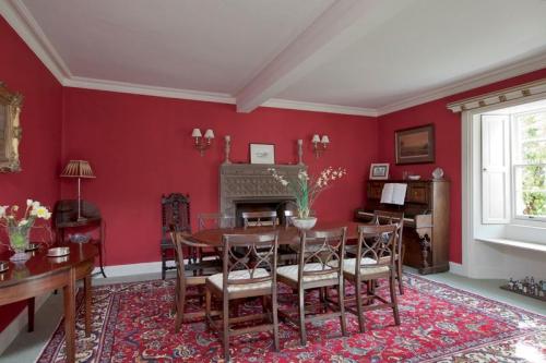 Red dining hall with dining table, chairs and view of garden